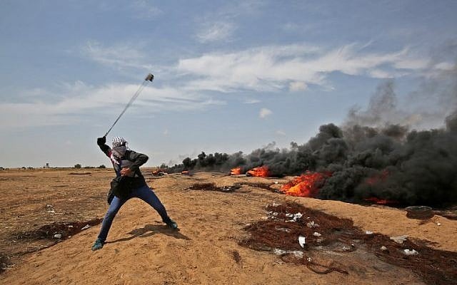 Un Palestinien armé d'une fronde jette des pierres aux soldats israéliens près de Khan Younis dans le sud de la bande de Gaza, au cours du cinquième vendredi consécutif d'émeutes massives le long de la frontière entre Gaza et Israël, le 27 avril 2018 (Crédit : AFP Photo/Said Khatib) Un Palestinien armé d'une fronde jette des pierres aux soldats israéliens près de Khan Younis dans le sud de la bande de Gaza, au cours du cinquième vendredi consécutif d'émeutes massives le long de la frontière entre Gaza et Israël, le 27 avril 2018 (Crédit : AFP Photo/Said Khatib)