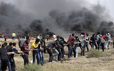 Des Palestiniens tentent de détruire la barrière entre Israël et la bande de Gaza à l'est de Jabaliya, au nord de l'enclave, au cinquième vendredi de protestations, le 27 avril 2018 (Crédit : AFP /Mahmud Hams)
