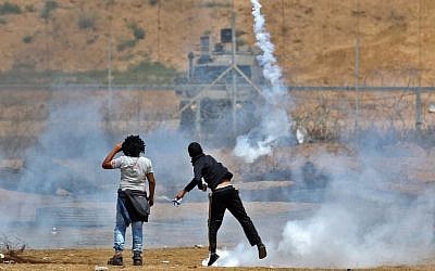 Un manifestant palestinien jette une bonbonne de gaz en direction des toupes israéliennes près de Khan Younis, au sud de la bande de Gaza au cinquième vendredi de protestations., le 27 avril 2018. (Crédit : AFP /Said Khatib)