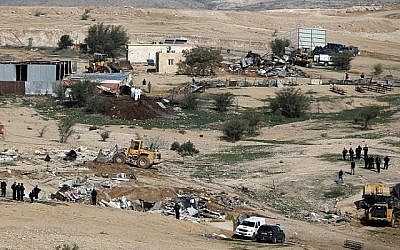 Des policiers israéliens montent la garde alors que des bulldozers démolissent des maisons dans le village bédouin illégal d'Oum al-Hiran, dans le désert du Néguev, le 18 janvier 2017. (AFP Photo/Menahem Kahana)