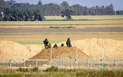 Des soldats israéliens regardent des manifestants palestiniens suite à une manifestation aux abords de la frontière avec Israël, à l'est de Khan Younis, dans le sud de la bande de Gaza, le 31 mars 2018 (Crédit : Abed Rahim Khatib/ Flash90)