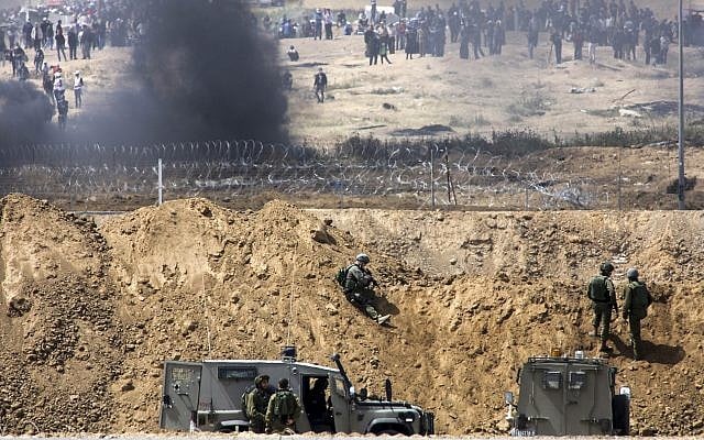 Des manifestants palestiniens brûlent des pneus près de la frontière avec Israël dans la bande de Gaza, vu du côté israélien de la frontière, le 13 avril 2018. (Sliman Khader/Flash90) Des manifestants palestiniens brûlent des pneus près de la frontière avec Israël dans la bande de Gaza, vu du côté israélien de la frontière, le 13 avril 2018. (Sliman Khader/Flash90)
