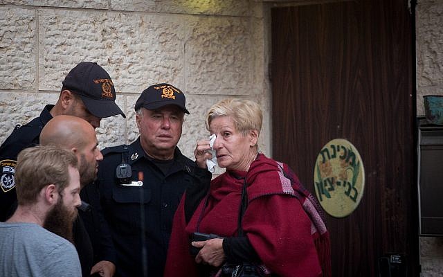 Une femme pleure aux côtés d'agents de police devant l'académie prémilitaire Benny Tzion de Tel Aviv qui avait organisé une randonnée qui a causé la mort de 9 adolescents dans la journée, le 26 avril 2018 (Crédit : Miriam Alster/Flash90) Une femme pleure aux côtés d'agents de police devant l'académie prémilitaire Benny Tzion de Tel Aviv qui avait organisé une randonnée qui a causé la mort de 9 adolescents dans la journée, le 26 avril 2018 (Crédit : Miriam Alster/Flash90)
