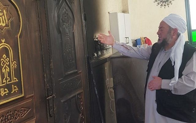 Un imam dans une mosquée du village palestinien d'Aqraba, dans le nord de la Cisjordanie, montre les dégâts causés par un incendie criminel survenu le 13 avril 2018. (Crédit : Zacharia Sadeh / Rabbis for Human Rights) Un imam dans une mosquée du village palestinien d'Aqraba, dans le nord de la Cisjordanie, montre les dégâts causés par un incendie criminel survenu le 13 avril 2018. (Crédit : Zacharia Sadeh / Rabbis for Human Rights)