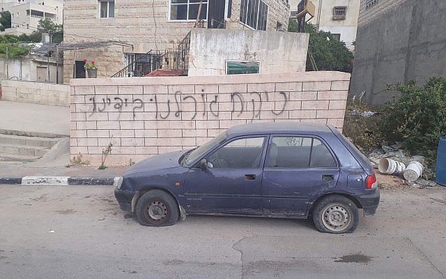 Des graffitis découverts sur un mur près d'une voiture dont les pneus ont été lacérés dans le village palestinien de Deir Ammar, près de Qalqilya, le 25 avril 2018 (Crédit : Police d'Israël) Des graffitis découverts sur un mur près d'une voiture dont les pneus ont été lacérés dans le village palestinien de Deir Ammar, près de Qalqilya, le 25 avril 2018 (Crédit : Police d'Israël)