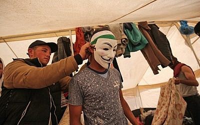 Un Palestinien aidé à attacher un masque alors qu'il se prépare à protester contre la frontière entre Israël et Gaza près de Khan Yunis, à l'est de la ville de Gaza, le 6 avril 2018 (Crédit : Photo AFP / SAID KHATIB)