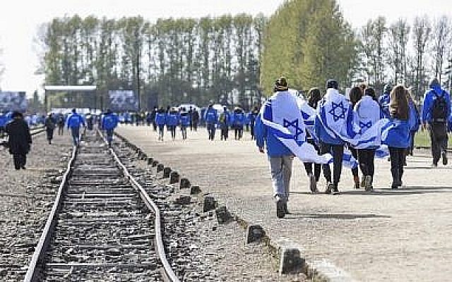 Des participants portant des drapeaux israéliens à l'ancien camp de concentration et d'extermination nazi-allemand Auschwitz-Birkenau lors de la «Marche des vivants» à Oswiecim à Cracovie, en Pologne, le 24 avril 2017 (Crédit : Omar Marques / Agence Anadolu / Getty Images via JTA) Des participants portant des drapeaux israéliens à l'ancien camp de concentration et d'extermination nazi-allemand Auschwitz-Birkenau lors de la «Marche des vivants» à Oswiecim à Cracovie, en Pologne, le 24 avril 2017 (Crédit : Omar Marques / Agence Anadolu / Getty Images via JTA)