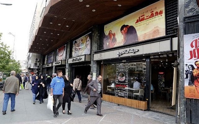 Des iraniens devant l'affiche du "Be Vaght-e Cham" ("À l’heure de Damas"), à Téhéran, le 1 mai 2018. (crédit : AFP/ATTA KENARE)