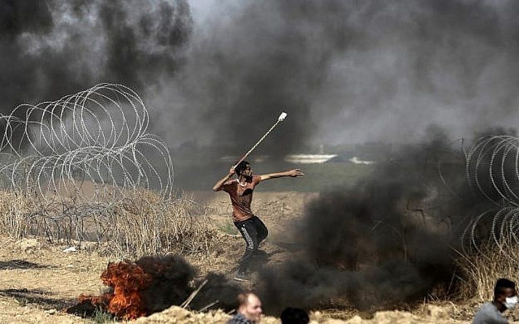 Un émeutier palestinien jette des pierres lors d'affrontements avec les forces israéliennes le long de la frontière avec la bande de Gaza, à l'est de la ville de Gaza, le 11 mai 2018 (Crédit : AFP / MAHMUD HAMS). Un émeutier palestinien jette des pierres lors d'affrontements avec les forces israéliennes le long de la frontière avec la bande de Gaza, à l'est de la ville de Gaza, le 11 mai 2018 (Crédit : AFP / MAHMUD HAMS).