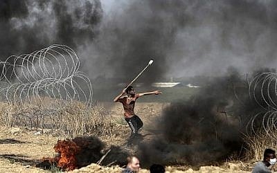 Un émeutier palestinien jette des pierres lors d'affrontements avec les forces israéliennes le long de la frontière avec la bande de Gaza, à l'est de la ville de Gaza, le 11 mai 2018 (Crédit : AFP / MAHMUD HAMS).
