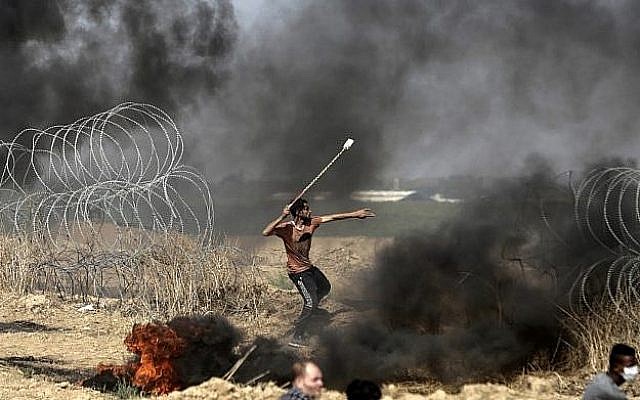 Un émeutier palestinien jette des pierres lors d'affrontements avec les forces israéliennes le long de la frontière avec la bande de Gaza, à l'est de la ville de Gaza, le 11 mai 2018 (Crédit : AFP / MAHMUD HAMS). Un émeutier palestinien jette des pierres lors d'affrontements avec les forces israéliennes le long de la frontière avec la bande de Gaza, à l'est de la ville de Gaza, le 11 mai 2018 (Crédit : AFP / MAHMUD HAMS).