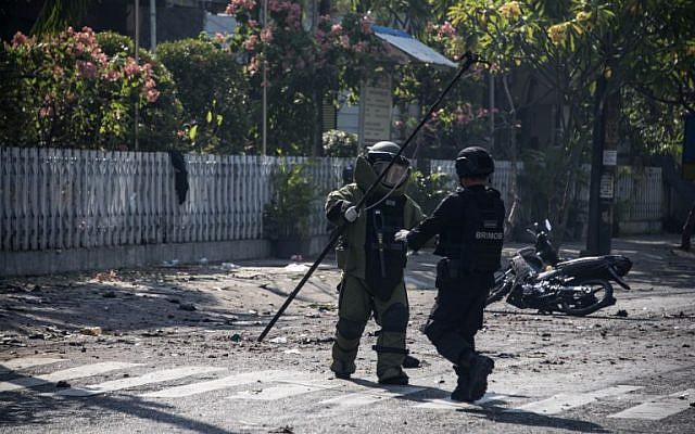 Des membres de la police antiterroriste indonésienne examinent le site d'un attentat-suicide à la bombe aux abords d'une église de Surabaya, le 13 mai 2018 (Crédit :  / AFP PHOTO / JUNI KRISWANTO)