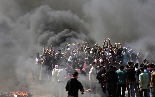 Des émeutiers palestiniens brûlent des peux à la frontière entre Israël et Gaza, à l'est de Gaza City, pour protester contre le transfert de l'ambassade américaine à Jérusalem, le 14 mai 2018. (Crédit : AFP /Mahmud Hams)