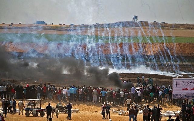 Des émeutiers palestiniens au milieu des gaz lacrymogènes et de la fumée émanant des pneus brûlés, à l'est de Gaza City, le 14 mai 2018. (Crédit : AFP/ Mohammed Abed) Des émeutiers palestiniens au milieu des gaz lacrymogènes et de la fumée émanant des pneus brûlés, à l'est de Gaza City, le 14 mai 2018. (Crédit : AFP/ Mohammed Abed)