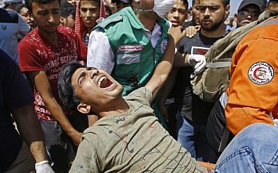 Les services d'urgence et des Palestiniens transportent un manifestant blessé lors d'affrontements avec les forces de sécurité israéliennes près de la frontière entre Israël et la bande de Gaza, à l'est de Jabalia, le 14 mai 2018 (AFP/Mohamed Abed).