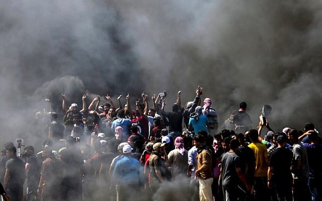 Des Palestiniens scandent des slogans lors d'affrontements avec les forces de sécurité israéliennes près de la frontière entre la bande de Gaza et Israël à l'est de la ville de Gaza le 14 mai 2018. (MAHMUD HAMS/AFP) Des Palestiniens scandent des slogans lors d'affrontements avec les forces de sécurité israéliennes près de la frontière entre la bande de Gaza et Israël à l'est de la ville de Gaza le 14 mai 2018. (MAHMUD HAMS/AFP)