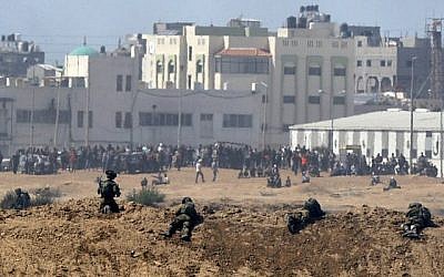 Une photo prise le 14 mai 2018 depuis le kibboutz israélien de Nahal Oz, de l'autre côté de la frontière avec la bande de Gaza, montrant des soldats israéliens qui se tiennent en position et des manifestants palestiniens qui manifestent le long de la frontière avec Israël (AFP / JACK GUEZ)