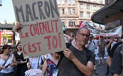 Un homme brandit une pancarte anti-Macron pendant un rassemblement organisé par un collectif d'organisations de gauche et d'extrême-gauche, à Strasbourg, le 26 mai 2018. (Crédit : AFP / PATRICK HERTZOG)