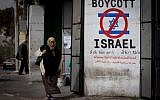 Une Palestinienne marche devant une pancarte appelant au boycott d'Israël dans la ville de Bethléem en Cisjordanie, le 11 février 2015 (Miriam Alster / Flash 90)