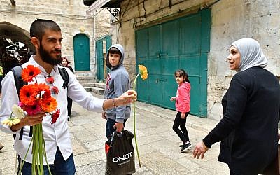 Un activiste de Tag Meir, organisation financée par le New Israel Fund, distribue une fleur à une femme musulmane dans la Vieille Ville de Jérusalem le 13 mai 2018, le jour de Yom Yeroushalayim. (Crédit : Rafi Kutz / Tag Meir)