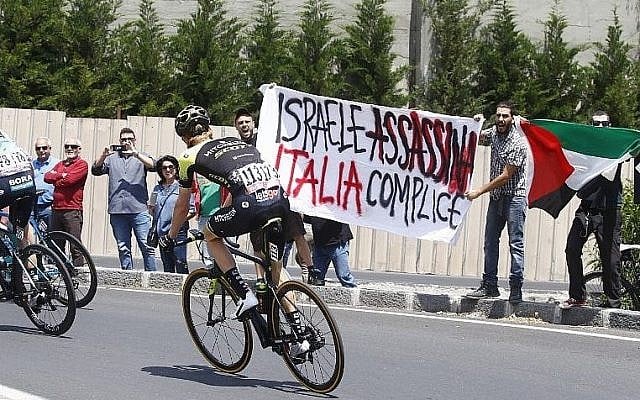 Illustration : Des manifestants anti-Israël brandissant un panneau disant "Israël assassine, l'Italie complice" avant le début de la 4ème étape du Giro d'Italie entre Catania et Caltagirone, en Sicile, le 8 mai 2017. (Crédit : Luk Benies/AFP) Illustration : Des manifestants anti-Israël brandissant un panneau disant "Israël assassine, l'Italie complice" avant le début de la 4ème étape du Giro d'Italie entre Catania et Caltagirone, en Sicile, le 8 mai 2017. (Crédit : Luk Benies/AFP)