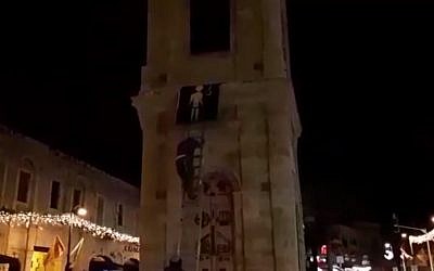 Des activistes d'extrême droite du groupe Otzma Yehudit suspendent la photo d'un terroriste sur une montre de la ville de Jaffa. (Crédit : capture d'écran Ynet)
