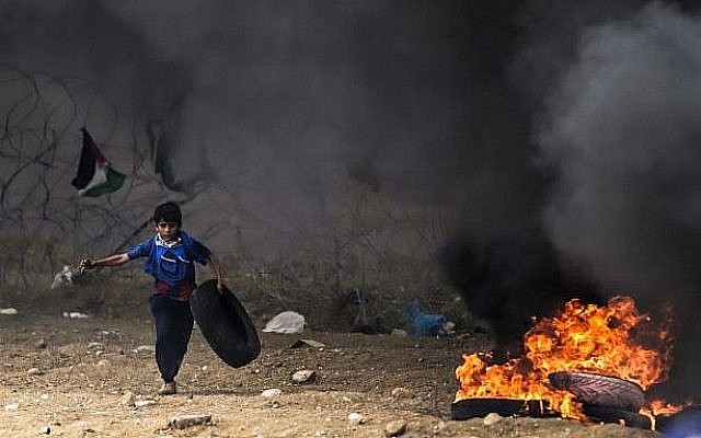 Un enfant palestinien court avec un pneu lors d'affrontements avec les forces israéliennes le long de la frontière avec la bande de Gaza à l'est de la ville de Gaza, le 4 mai 2018 (AFP PHOTO / MAHMUD HAMS)
