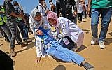 Razan al-Najjar (D), une secouriste palestinienne de 21 ans, soigne une collègue blessée lors d'affrontements près de la frontière avec Israël, à l'est de Khan Younès, dans le sud de la bande de Gaza, le 15 mai 2018. (Crédit : AFP/ DIT KHATIB)