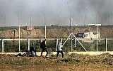Un Palestinien jette des pierres sur les forces israéliennes alors que de la fumée s'élève des pneus brûlés durant une manifestation le long de la frontière avec la bande de Gaza, à l'est de Gaza city, le 1er juin 2018 (Crédit :  / AFP PHOTO / Mahmud Hams)