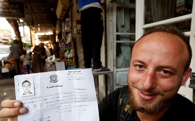 Le combattant syrien Mohammad Damour brandit le document attestant de sa démobilisation de l'armée syrienne, à Damas,le 4 juin 2018. (Crédit : AFP / LOUAI BESHARA) Le combattant syrien Mohammad Damour brandit le document attestant de sa démobilisation de l'armée syrienne, à Damas,le 4 juin 2018. (Crédit : AFP / LOUAI BESHARA)