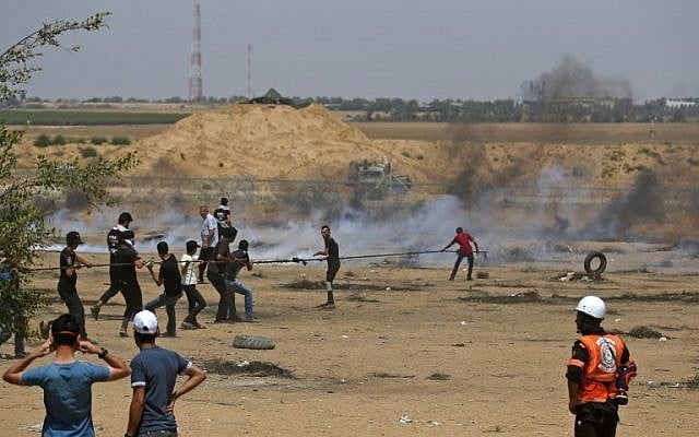 Illustration: Des Palestiniens tirent sur un câble attaché à une clôture en fil barbelé dans le but d'abattre une section de la clôture avec Israël, lors d'affrontements frontaliers à l'est de Khan Younès dans le sud de la bande de Gaza, le 8 juin 2018. (AFP Photo/Said Khatib) Illustration: Des Palestiniens tirent sur un câble attaché à une clôture en fil barbelé dans le but d'abattre une section de la clôture avec Israël, lors d'affrontements frontaliers à l'est de Khan Younès dans le sud de la bande de Gaza, le 8 juin 2018. (AFP Photo/Said Khatib)