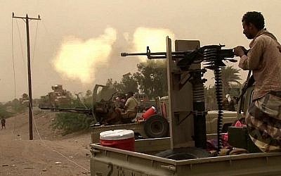 Un combattant pro-gouvernement yéménite brûle un prospectus avec le slogan : "Dieu est le plus grand... Mort à l'Amérique, mort à Israël, maudits soient les Juifs, victoire pour l'Islam" à son arrivée dans le quartier d' al-Durayhimi à environ neuf kilomètres au sud de l'aéroport international de Hodeidah, le 13 juin 2018 (Crédit :  AFP Photo/Nabil Hassan)
