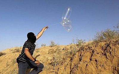 Un Palestinien masqué lance un ballon chargé de matières inflammables en direction d'Israël depuis la ville de Rafah, au sud de Gaza, le 17 juin 2018. (AFP Photo/Said Khatib)