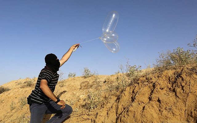 Un Palestinien masqué lance un ballon chargé de matières inflammables en direction d'Israël depuis la ville de Rafah, au sud de Gaza, le 17 juin 2018. (AFP Photo/Said Khatib) Un Palestinien masqué lance un ballon chargé de matières inflammables en direction d'Israël depuis la ville de Rafah, au sud de Gaza, le 17 juin 2018. (AFP Photo/Said Khatib)