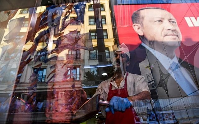 Tandis qu'un boucher tranche de la viande, l'on aperçoit le reflet d'un portrait du président turc Recep Tayyip Erdogan dans la fenêtre d'un restaurant turc sur la place Taksim d'Istanbul le 20 juin 2018. (Crédit : AFP / Bulent Kilic) Tandis qu'un boucher tranche de la viande, l'on aperçoit le reflet d'un portrait du président turc Recep Tayyip Erdogan dans la fenêtre d'un restaurant turc sur la place Taksim d'Istanbul le 20 juin 2018. (Crédit : AFP / Bulent Kilic)