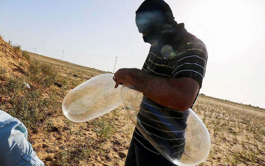 Un Palestinien masqué prépare des ballons auxquels seront attachés des matériaux inflammables et qui seront lancés en direction du territoire israélien, à Rafah, le 17 juin 2018. (Crédit : Abed Rahim Khatib/Flash90) Un Palestinien masqué prépare des ballons auxquels seront attachés des matériaux inflammables et qui seront lancés en direction du territoire israélien, à Rafah, le 17 juin 2018. (Crédit : Abed Rahim Khatib/Flash90)