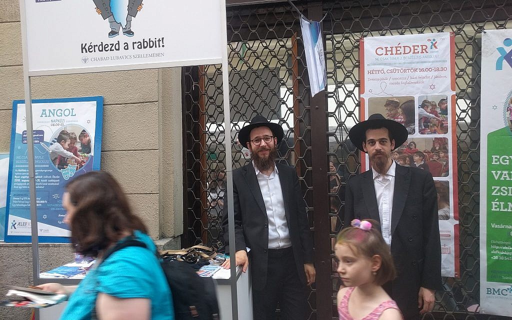 Les délégués Habad, les rabbins Yitzchak Stell, (à gauche), et Chaim Shaul Glitzinstein, proposent aux passants de prier et de mettre les phylactères au festival de rue Judafest à Budapest, le 10 juin 2018. (Yaakov Schwartz/ Times of Israel)