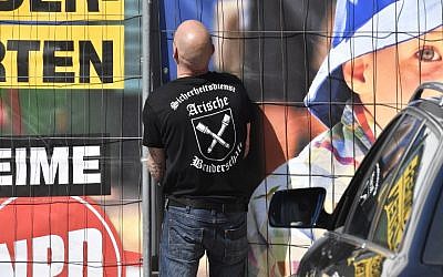 Un gardien de sécurité privé avec "la fraternité aryenne" sur son tee-shirt ouvre la porte du lieu du festival néo-nazi  'Schild und Schwert' (bouclier et épée) dans la petite ville d'Ostritz, à l'est de l'Allemagne, le 20 avril 2018 (Crédit :  AFP / John MACDOUGALL)
