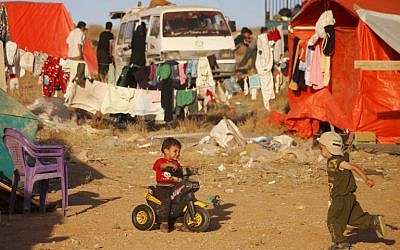 Des enfants syriens de la province de Deraa qui ont fui les bombardements de forces pro-gouvernementales attendent de pouvoir franchir la frontière jordanienne, à Nassib, le 1er juillet 2018. (Crédit : AFP / Mohamad ABAZEED)