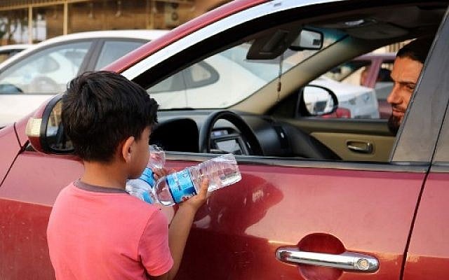 Un enfant irakien vend des bouteilles d'eau à des conducteurs circulant dans une rue de la ville de Mossoul, dans le nord de l'Irak, le 7 juillet 2018. (Crédit : AFP / Waleed AL-KHALID)