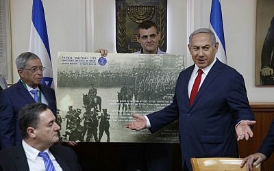 Le Premier ministre israélien Benjamin Netanyahu (d) reçoit un cadeau de l'Institut Zeev Jabotinsky lors de la réunion hebdomadaire du cabinet à Jérusalem, le 8 juillet 2018. (Crédit : AFP/POOL/ABIR SULTAN)