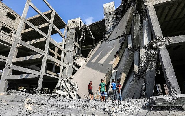 Des petits Palestiniens marchent sur les débris d'un immeuble endommagé par les frappes aériennes israéliennes à Gaza City, le 15 juillet 2018 (Crédit : AFP / MAHMUD HAMS) Des petits Palestiniens marchent sur les débris d'un immeuble endommagé par les frappes aériennes israéliennes à Gaza City, le 15 juillet 2018 (Crédit : AFP / MAHMUD HAMS)