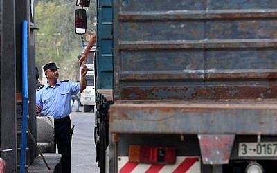 Un agent de sécurité palestinien vérifie les papiers d'un chauffeur de camion au point de passage de Kerem Shalom, important des denrées alimentaires dans la bande de Gaza, le 17 juillet 2018. (Crédit : AFP / SAID KHATIB)