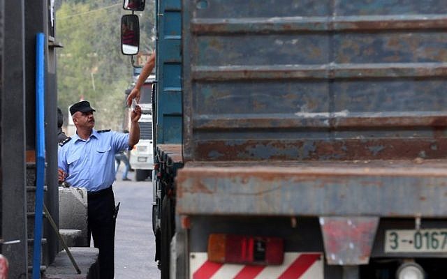 Un agent de sécurité palestinien vérifie les papiers d'un chauffeur de camion au point de passage de Kerem Shalom, important des denrées alimentaires dans la bande de Gaza, le 17 juillet 2018. (Crédit : AFP / SAID KHATIB) Un agent de sécurité palestinien vérifie les papiers d'un chauffeur de camion au point de passage de Kerem Shalom, important des denrées alimentaires dans la bande de Gaza, le 17 juillet 2018. (Crédit : AFP / SAID KHATIB)