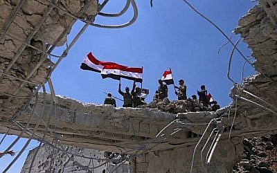 Les forces gouvernementales syriennes brandissent le drapeau national après avoir repris aux rebelles la ville de Quneitra, le 19 juillet 2018 (Crédit : AFP PHOTO / Youssef KARWASHAN)