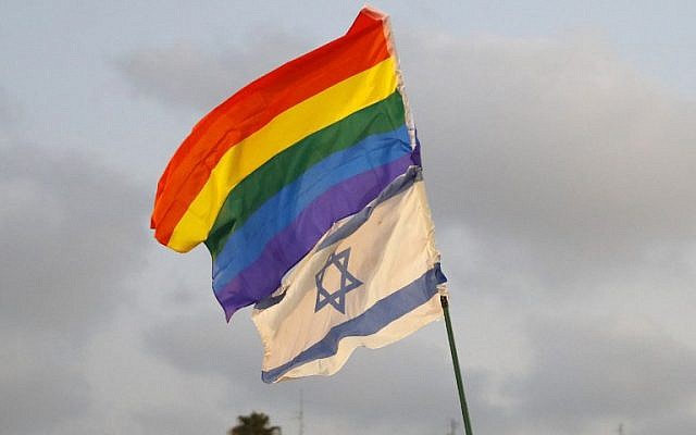 Les participants font voler un drapeau israélien et celui de la fierté lors d'une manifestation à Tel-Aviv le 22 juillet 2018, pour protester contre une nouvelle loi sur les mères porteuses qui n'inclut pas les couples homosexuels. (Crédit : AFP / JACK GUEZ)