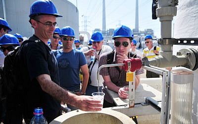Des visiteurs remplissent leurs verres avec de l'eau de mer traitée dans une usine de dessalement près de Hadera, en Israël.(Crédit : Shay Levy / Flash90)