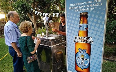 Des invités goûtent la nouvelle bière germano-israélienne appelée "70" à la résidence de l'ambassadeur allemand en Israël Clemens von Goetze à Herzliya, le 19 juillet 2018 (Crédit : Raphael Ahren/TOI)