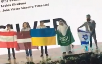 L'étudiant saoudien Badr al-Mulhim, 2ème à droite, est vu avec son drapeau et se préparant à se déplacer à l'arrivée de l'Israélien Raz Lotan, à droite, qui porte les couleurs de l'Etat juif lors de la 50ème édition des olympiades internationales de Chimie, en Slovaquie et en république tchèque, dans une vidéo publiée sur internet le 29 juillet 2018 (Capture d'écran : Twitter)