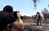 Un photographe prend un cliché de Dana et Itai Nisanov parmi les arbres brûlés à proximité de la frontière avec Gaza (Capture d'écran : Hadashot news)